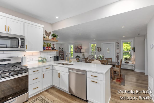 10840 Harvard Ave NE, Rockford, MI 49341 - kitchen featuring appliances with stainless steel finishes, a peninsula, recessed lighting, light wood-style flooring, and decorative backsplash