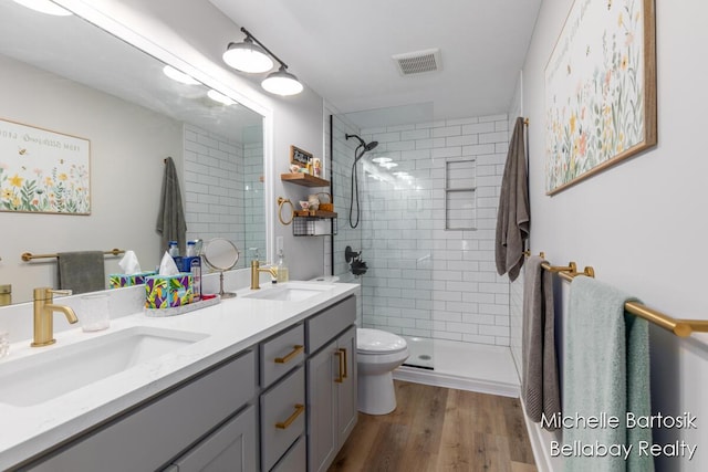 10840 Harvard Ave NE, Rockford, MI 49341 - bathroom featuring double vanity, tiled shower, and wood finished floors