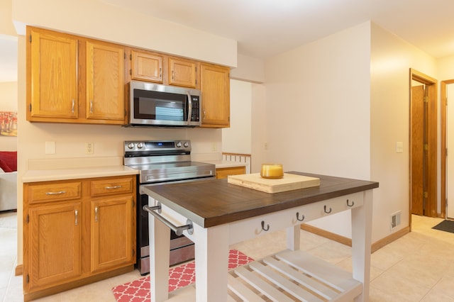 1428 Sherry Dr, Portage, MI 49024 - kitchen with appliances with stainless steel finishes, light tile patterned flooring, brown cabinetry, and butcher block countertops