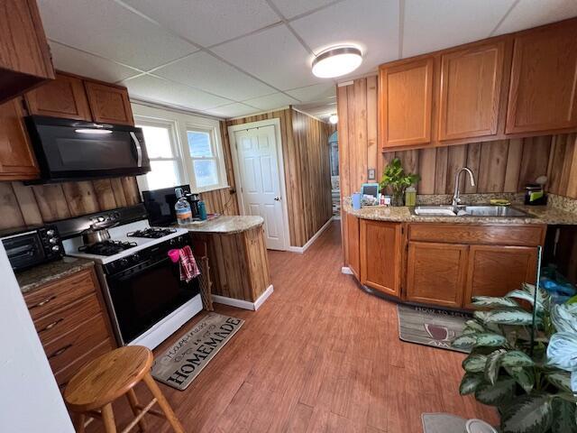 1325 Maude Ave NE, Grand Rapids, MI 49505 - kitchen featuring gas stove, black microwave, light wood-style floors, brown cabinets, and a drop ceiling