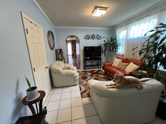 1325 Maude Ave NE, Grand Rapids, MI 49505 - living area featuring arched walkways, a textured ceiling, crown molding, and light tile patterned floors