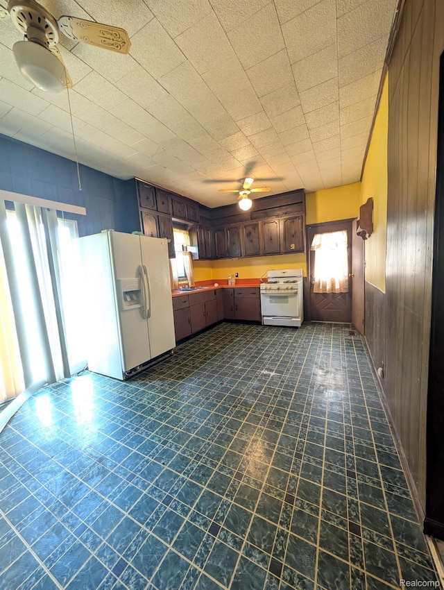 1402 Allen St, Burton, MI 48529 - kitchen with white appliances, ceiling fan, wooden walls, and dark brown cabinets