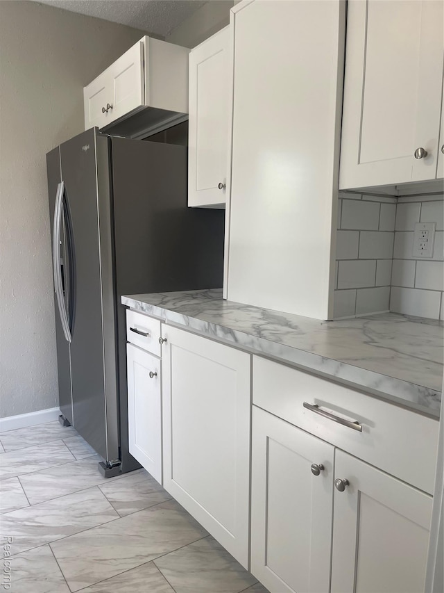 160 Emmons Blvd, Wyandotte, MI 48192 - kitchen with white cabinets, light marble finish flooring, tasteful backsplash, freestanding refrigerator, and light stone counters