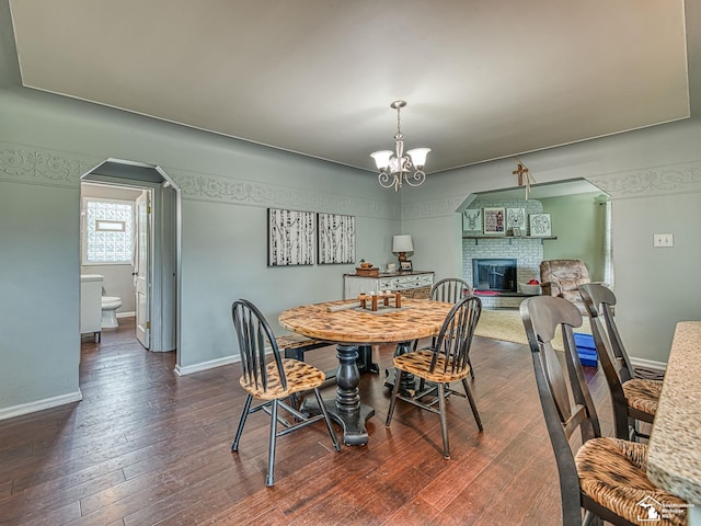 5825 Edgewood Blvd, Monroe, MI 48161 - dining room with a fireplace, a chandelier, arched walkways, and dark wood-type flooring