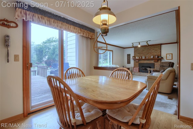 21905 Roxbury Dr, Novi, MI 48374 - dining room featuring a brick fireplace, light wood-style flooring, track lighting, and ornamental molding