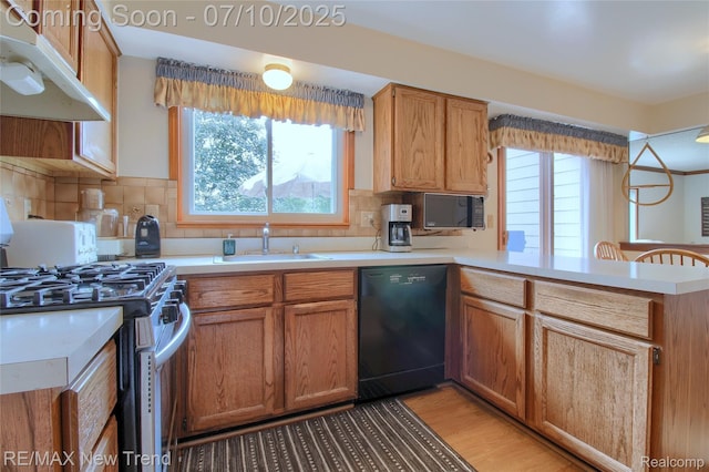 21905 Roxbury Dr, Novi, MI 48374 - kitchen with dishwasher, stainless steel range with gas cooktop, under cabinet range hood, a peninsula, and light countertops