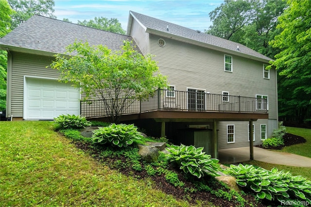 12151 Vergennes St, Lowell, MI 49331 - back of property featuring a yard, a wooden deck, a garage, a shingled roof, and a patio