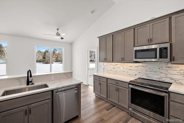 7268 Elizabeth Lake Rd, Waterford, MI 48327 - kitchen featuring stainless steel appliances, a ceiling fan, decorative backsplash, wood finished floors, and high vaulted ceiling