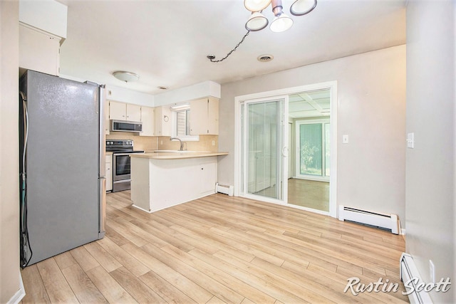 2953-2955 Okemos Dr SE, Grand Rapids, MI 49546 - kitchen featuring stainless steel appliances, a baseboard radiator, baseboard heating, a peninsula, and light wood-style flooring