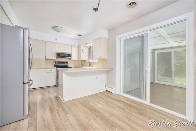 2953-2955 Okemos Dr SE, Grand Rapids, MI 49546 - kitchen with appliances with stainless steel finishes, a baseboard heating unit, a peninsula, light countertops, and light wood-style flooring