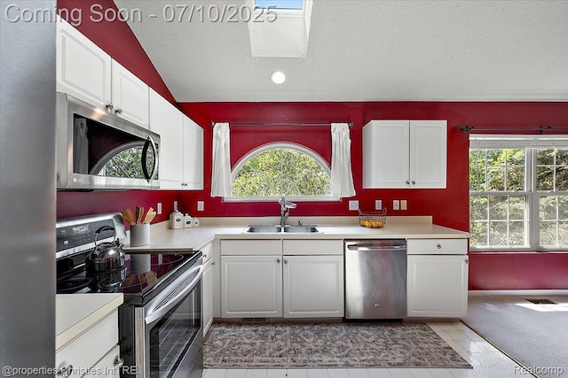 6873 Fox Ln, Waterford, MI 48327 - kitchen with stainless steel appliances, a textured ceiling, light countertops, white cabinetry, and vaulted ceiling