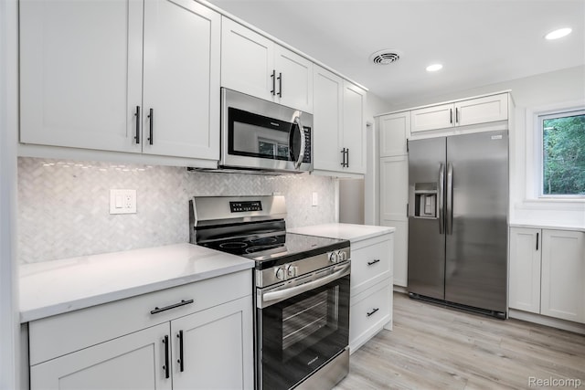 21710 Whitmore St, Oak Park, MI 48237 - kitchen featuring appliances with stainless steel finishes, tasteful backsplash, light wood-type flooring, recessed lighting, and white cabinetry