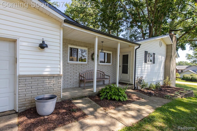 7709 Shelley Dr, Clarkston, MI 48348 - view of exterior entry with a porch, a garage, a chimney, and brick siding