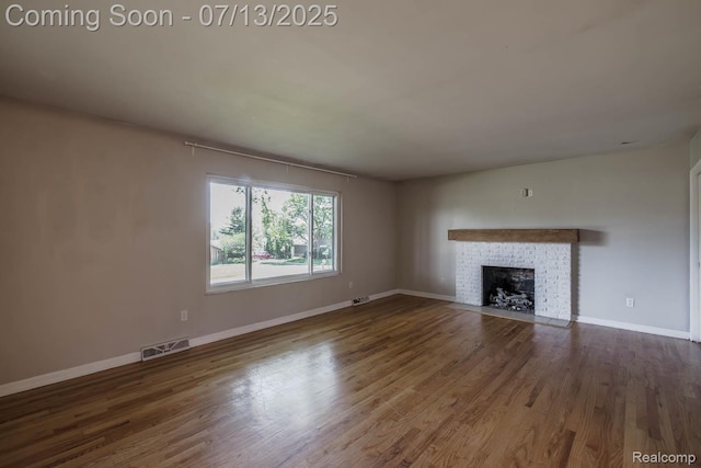 7709 Shelley Dr, Clarkston, MI 48348 - unfurnished living room featuring a brick fireplace and wood finished floors