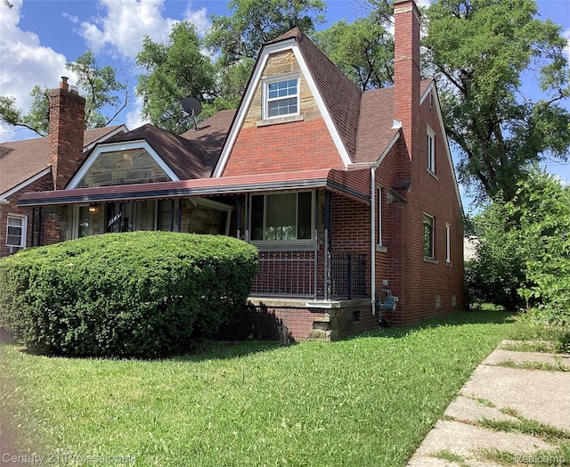 15451 Prest St, Detroit, MI 48227 - tudor house with a front lawn, a chimney, brick siding, and a porch