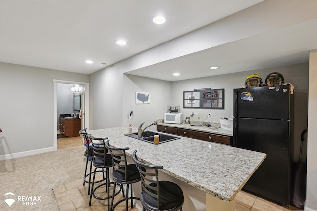 7266 Dodge Rd, Montrose, MI 48457 - kitchen with freestanding refrigerator, white microwave, a breakfast bar, recessed lighting, and light stone countertops