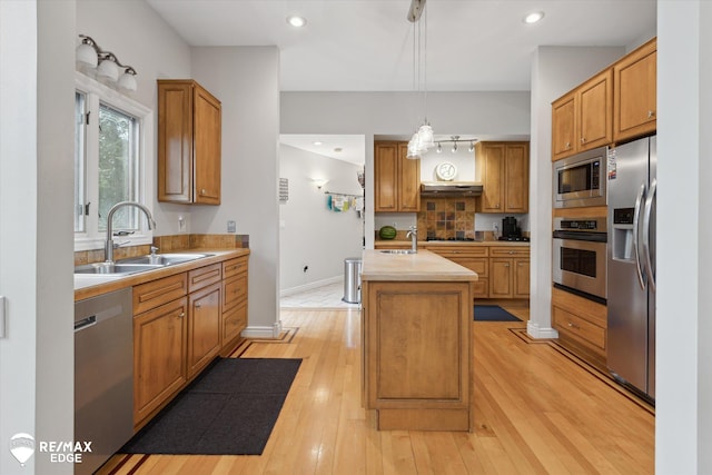 7266 Dodge Rd, Montrose, MI 48457 - kitchen with appliances with stainless steel finishes, a kitchen island with sink, light countertops, tasteful backsplash, and light wood finished floors