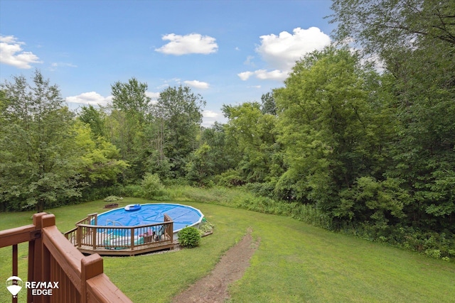 7266 Dodge Rd, Montrose, MI 48457 - view of grassy yard featuring a covered pool, a deck, and a wooded view
