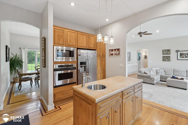 7266 Dodge Rd, Montrose, MI 48457 - kitchen with stainless steel appliances, arched walkways, light wood-type flooring, a kitchen island with sink, and recessed lighting