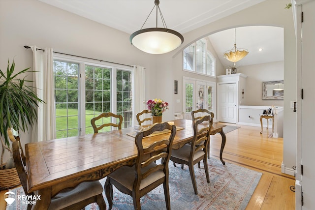 7266 Dodge Rd, Montrose, MI 48457 - dining room featuring healthy amount of natural light, vaulted ceiling, arched walkways, light wood-style floors, and wainscoting