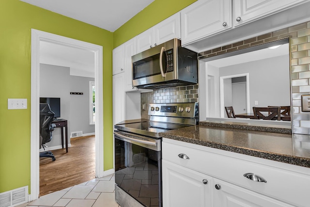 723 S Bowen St, Jackson, MI 49203 - kitchen with stainless steel appliances, white cabinetry, backsplash, dark stone countertops, and light wood-style floors