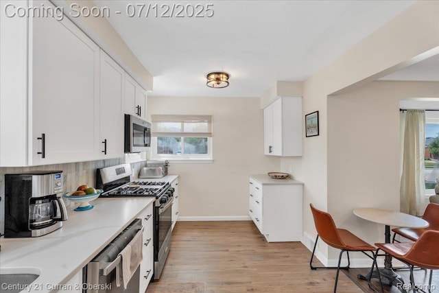 23139 Deziel St, Saint Clair Shores, MI 48082 - kitchen featuring stainless steel appliances, light wood finished floors, white cabinetry, and backsplash