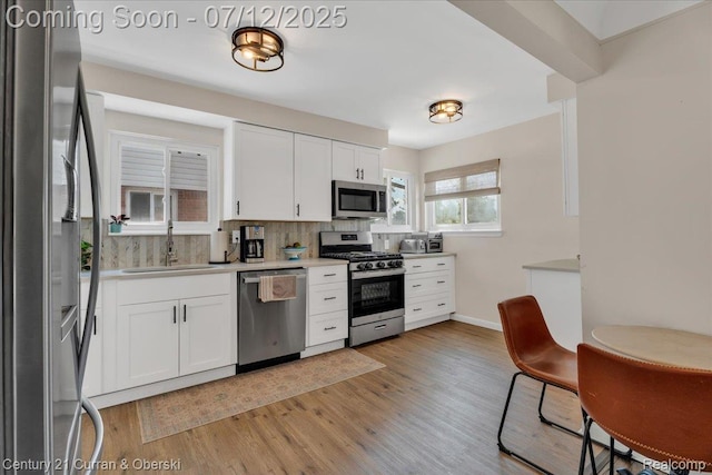 23139 Deziel St, Saint Clair Shores, MI 48082 - kitchen with appliances with stainless steel finishes, backsplash, white cabinetry, light countertops, and light wood-style flooring
