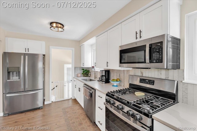 23139 Deziel St, Saint Clair Shores, MI 48082 - kitchen featuring appliances with stainless steel finishes, white cabinets, light countertops, light wood finished floors, and backsplash