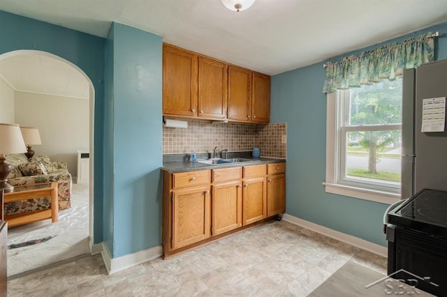 1312 Bayliss St, Midland, MI 48640 - kitchen with freestanding refrigerator, range with electric stovetop, brown cabinetry, and tasteful backsplash