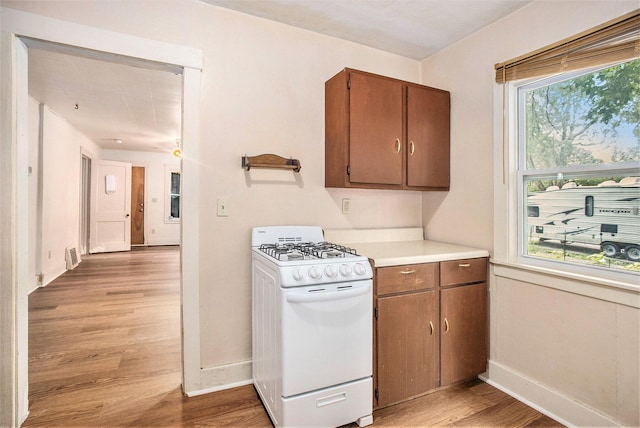 100 Eldred St, Battle Creek, MI 49015 - kitchen with white gas range, light wood-style floors, light countertops, and brown cabinets