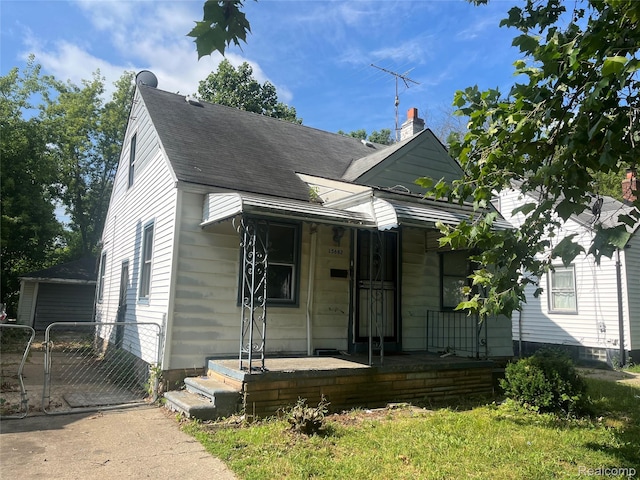 15682 Liberal St, Detroit, MI 48205 - bungalow-style home with a gate, covered porch, roof with shingles, a detached garage, and a chimney