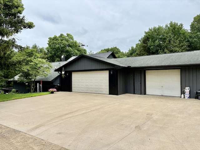 12141 Lawrence Rd, Brooklyn, MI 49230 - view of front of property with board and batten siding, an attached garage, a shingled roof, and driveway