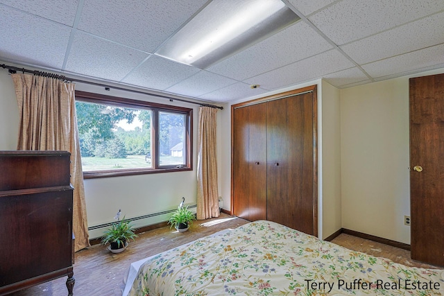 2860 Fenner Rd, Muskegon, MI 49445 - bedroom featuring a drop ceiling, wood finished floors, a closet, and baseboard heating