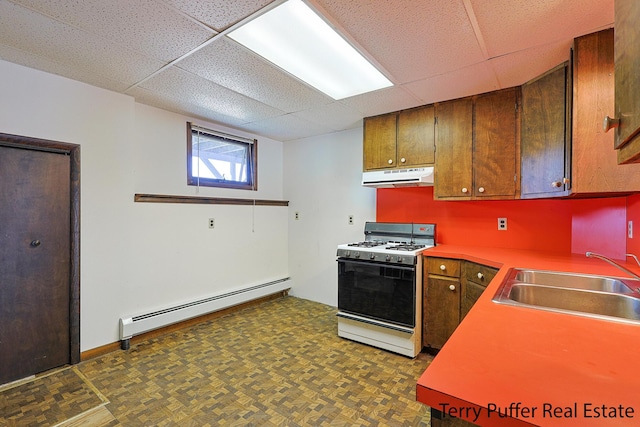 2860 Fenner Rd, Muskegon, MI 49445 - kitchen with gas range gas stove, under cabinet range hood, a baseboard radiator, a paneled ceiling, and brown cabinets