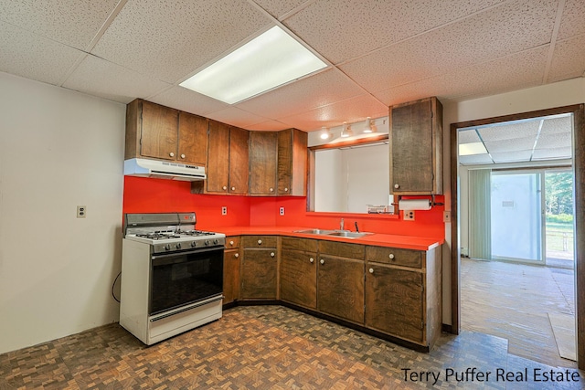 2860 Fenner Rd, Muskegon, MI 49445 - kitchen with gas range gas stove, under cabinet range hood, a drop ceiling, and brown cabinets