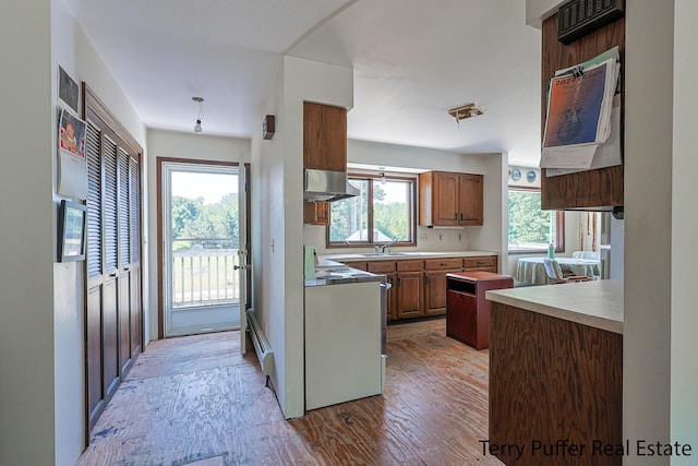 2860 Fenner Rd, Muskegon, MI 49445 - kitchen featuring stove, light wood-style floors, light countertops, wall chimney range hood, and brown cabinets