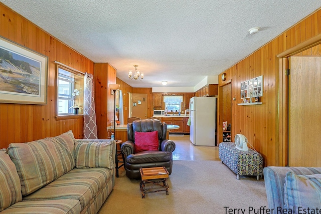 2860 Fenner Rd, Muskegon, MI 49445 - living area featuring wood walls, a chandelier, a textured ceiling, and light carpet