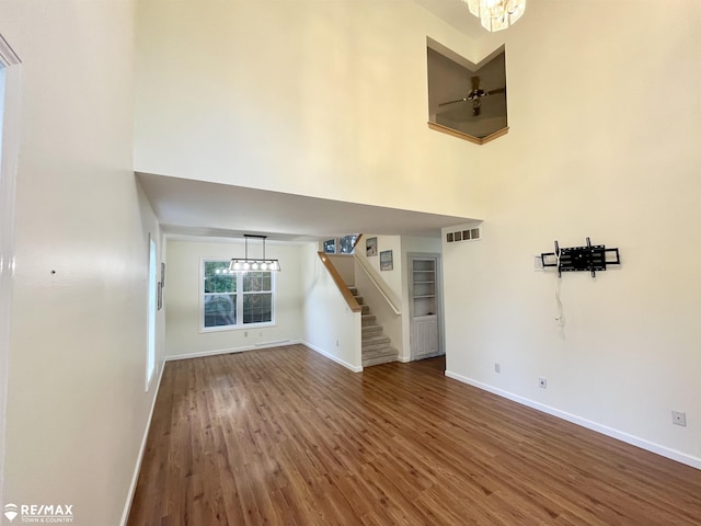 1421 Newcastle Dr, Davison, MI 48423 - unfurnished living room featuring a towering ceiling, stairway, wood finished floors, and a chandelier