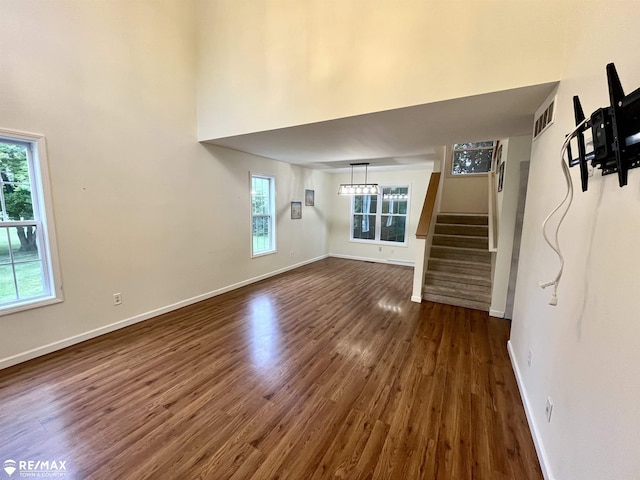 1421 Newcastle Dr, Davison, MI 48423 - unfurnished living room featuring dark wood-style floors, plenty of natural light, stairs, and a high ceiling