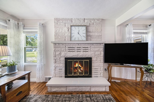 119 Burt Ave, Jackson, MI 49201 - living area with wood finished floors, a stone fireplace, and a textured ceiling
