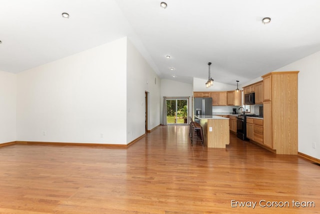 5599 Marsh Rd, Shelbyville, MI 49344 - kitchen with vaulted ceiling, open floor plan, black range oven, a kitchen breakfast bar, and stainless steel fridge
