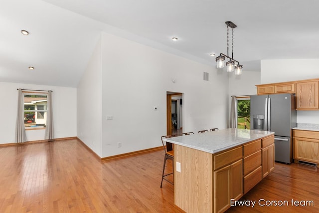 5599 Marsh Rd, Shelbyville, MI 49344 - kitchen featuring stainless steel refrigerator with ice dispenser, a kitchen breakfast bar, light wood-style floors, pendant lighting, and high vaulted ceiling