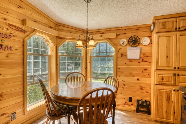 13113 Pinewood St NE, Gowen, MI 49326 - dining room with a textured ceiling, a chandelier, plenty of natural light, wood walls, and light wood-style floors