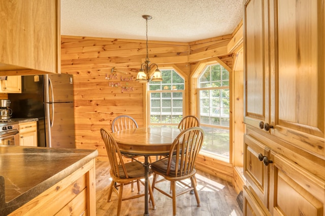 13113 Pinewood St NE, Gowen, MI 49326 - dining area with light wood-type flooring, a chandelier, wooden walls, and a textured ceiling