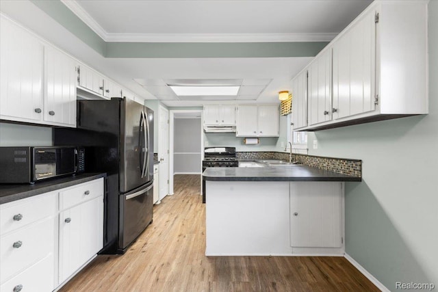 12360 Moers Dr, Sterling Heights, MI 48313 - kitchen featuring black microwave, light wood-style floors, dark countertops, under cabinet range hood, and a peninsula