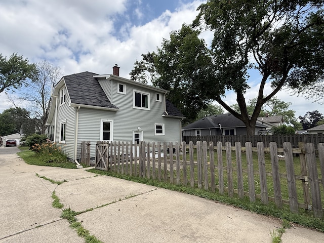 1316 Vassar Dr, Kalamazoo, MI 49001 - rear view of house featuring a chimney, roof with shingles, and a fenced front yard
