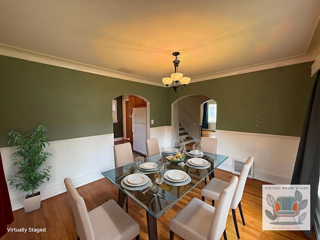 1316 Vassar Dr, Kalamazoo, MI 49001 - dining space with arched walkways, wainscoting, wood finished floors, stairway, and crown molding