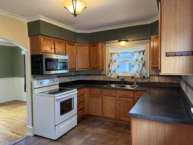 1316 Vassar Dr, Kalamazoo, MI 49001 - kitchen featuring white electric range, stainless steel microwave, dark countertops, arched walkways, and brown cabinetry