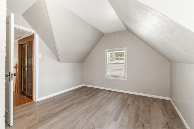 716 17th St, Jackson, MI 49203 - bonus room featuring wood finished floors, lofted ceiling, and a textured ceiling