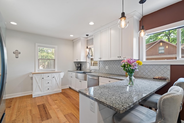 10637 Portage Rd, Portage, MI 49002 - kitchen with stainless steel dishwasher, white cabinetry, light wood-style flooring, a peninsula, and plenty of natural light